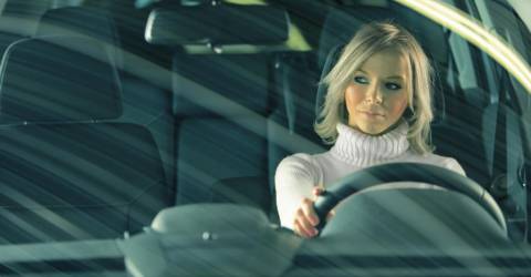 blond meisje rijd auto en kijkt in haar rechter spiegel